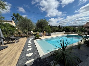 A swimming pool with a stone pathway, outdoor seating, and surrounding greenery. - Cocoon renovated Grasse (Grasse)