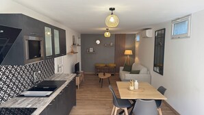 A modern kitchen with a microwave, a sink, and a patterned backsplash. There is a dining area with a table and chairs, and a sofa in the background. - Cocoon renovated Grasse (Grasse)