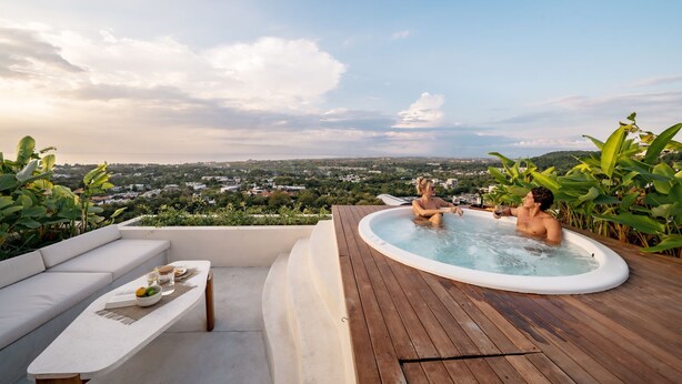 Eine Dachterrasse mit Whirlpool, Sitzgelegenheit und Blick auf die Stadtlandschaft.
