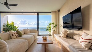 Ein modernes Wohnzimmer mit großem Fenster, Flachbildfernseher und Deckenventilator.
