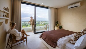 Ein Schlafzimmer mit einem großen Bett, einer Couch, einem Balkon mit Blick und einer Klimaanlage.