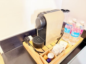 A coffee machine, bottled water, and cream on a tray. - Cozy 1-bedroom condo in peaceful Pasay City with AC (Pasay City)