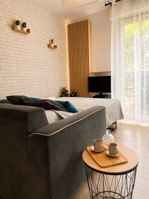 A modern bedroom with a sofa, a bed, a TV, and a small table with cups. - Large Studio in residence with swimming pool (Provence-Alpes-Côte d'Azur)