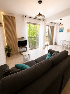 A modern living room with a sofa, TV, and a dining area with chairs. - Large Studio in residence with swimming pool (Provence-Alpes-Côte d'Azur)