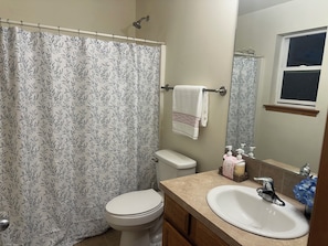 Une salle de bain équipée de toilettes, d’un lavabo, d’un rideau de douche, d’une serviette et d’articles de toilette.