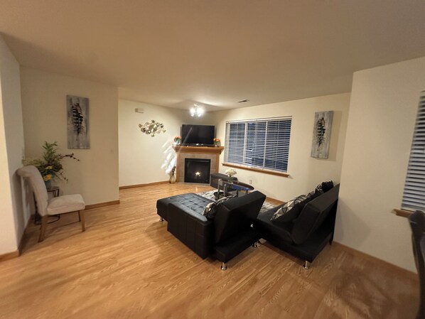 A living room with a fireplace, a TV, and a window with blinds.