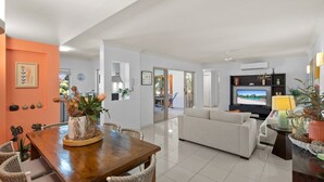 Een moderne woonkamer met een bank, televisie en een eethoek met een tafel en stoelen.