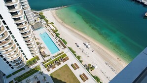 Ett högt hotell med pool, strand och småbåtshamn.