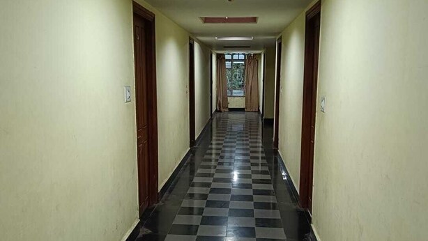 Un pasillo largo y estrecho con piso a cuadros negro y blanco, puertas a ambos lados y una lámpara en el techo.