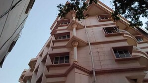 Un edificio de varios pisos con balcones, entrada a nivel de calle y un letrero de restaurante a la vista.