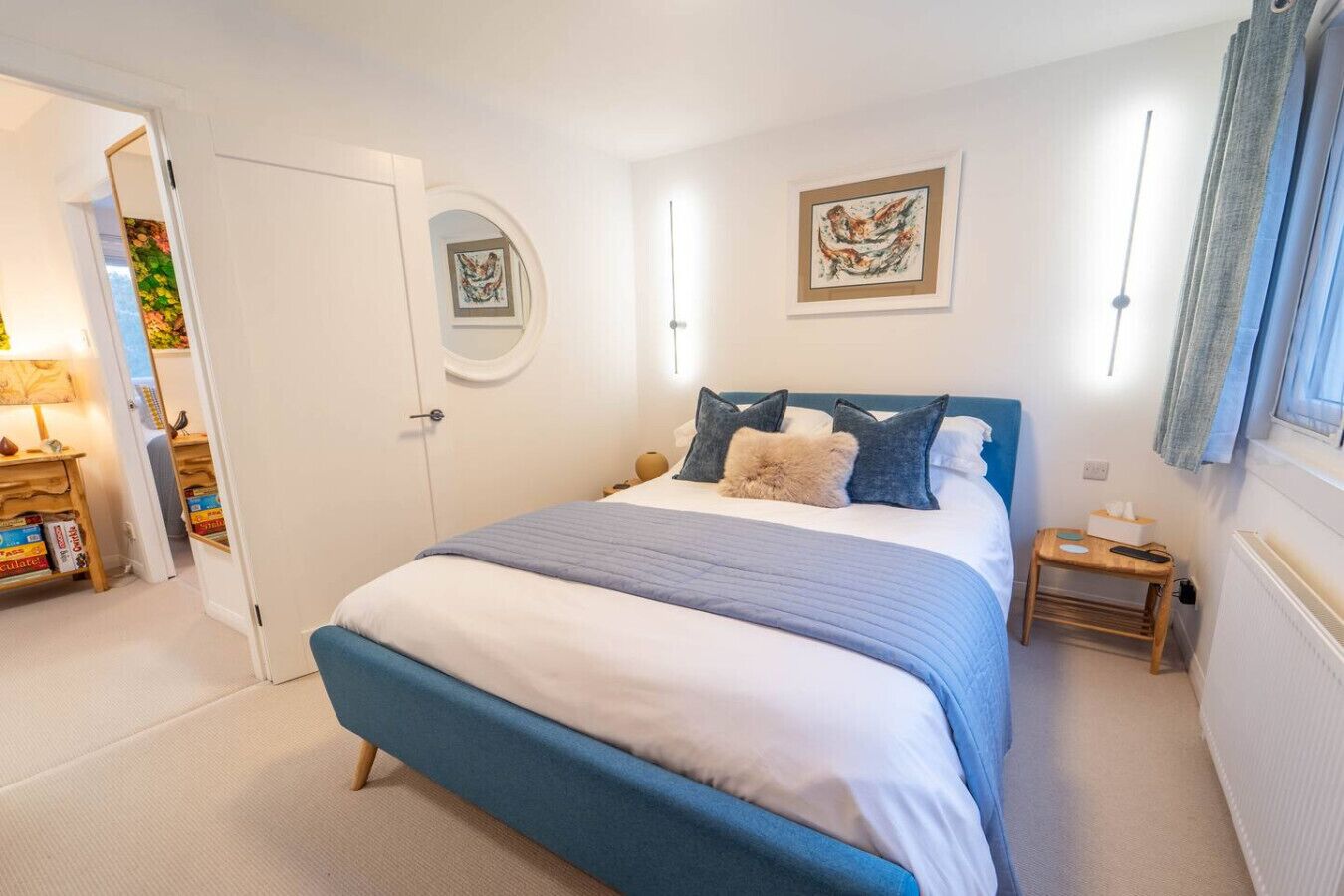 A bedroom with a bed, bedside tables, a mirror, and artwork on the walls.