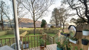 Een terras met uitzicht op een omheinde tuin, een houten schutting en een spiegel aan de muur.