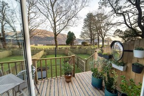 Eine Terrasse mit Blick auf einen von einer Holzlattenzaun umgebenen Garten, inklusive Spiegel an der Wand.