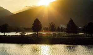 Una vista tranquilla su un lago, con montagne sullo sfondo e alcuni alberi sullo sfondo.