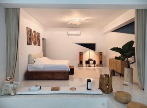 Una camera da letto moderna con un letto, comodini, una scrivania, una pianta e un'ampia finestra.