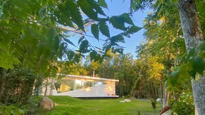 A modern house with a glass facade, surrounded by a well-maintained lawn and trees. - 台灣「台東十景」清晨無人的別墅區可眺望湖邊迎接美好假期最重要的一刻 (Chishang Township)
