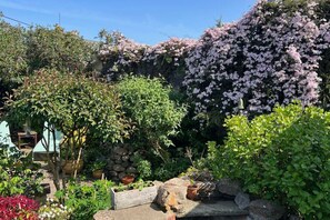 A garden with various plants, a stone wall, and a wooden structure. - Fife Cottage between St Andrews and Dundee (Fife)