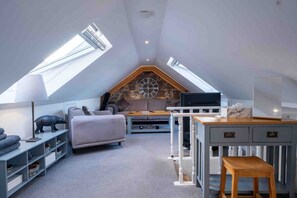 A loft bedroom with a sloped ceiling, skylights, a bed, a TV, and a desk area. - Fife Cottage between St Andrews and Dundee (Fife)