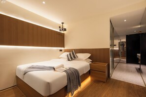 Quarto de hotel moderno com cama bem arrumada, mesas de cabeceira e armário embutido.