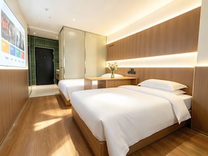 Ein Hotelzimmer mit zwei Betten, einem hölzernen Kopfteil, einem Nachttisch mit einer Vase und einer Wand mit grünen Fliesen.