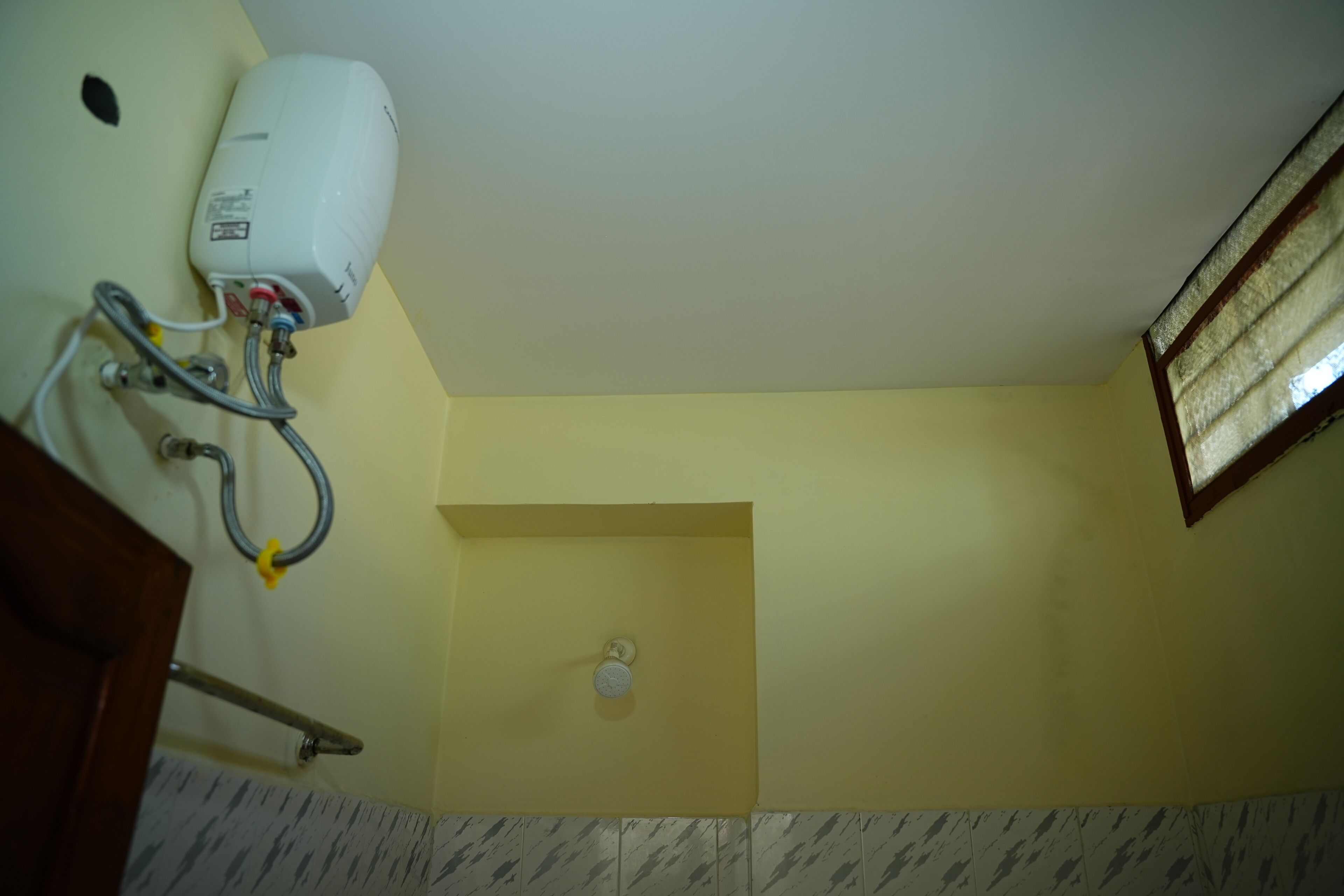 A bathroom with a hand dryer, a towel rack, and a showerhead.