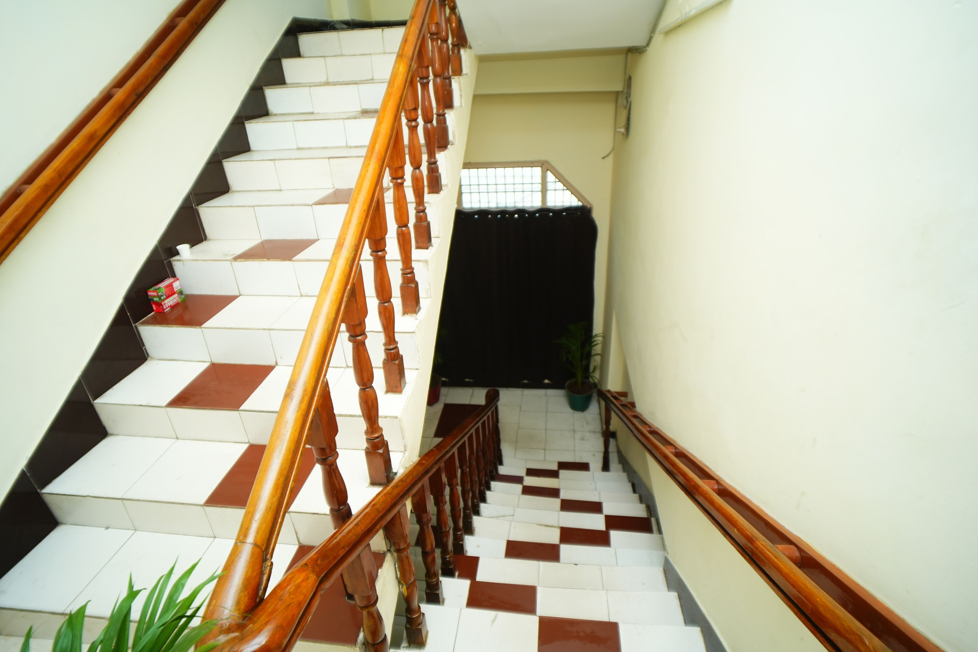 A staircase with wooden railings and checkered floor tiles.