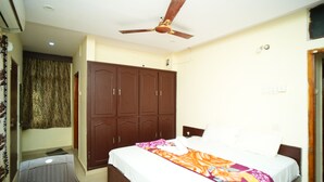 A bedroom with a bed, a wardrobe, a ceiling fan, and a chair. - SV Grand (Kakinada)