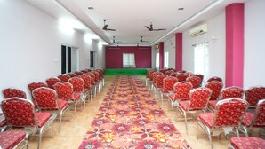 A conference room with rows of chairs, a green carpet, and ceiling fans. - SV Grand (Kakinada)