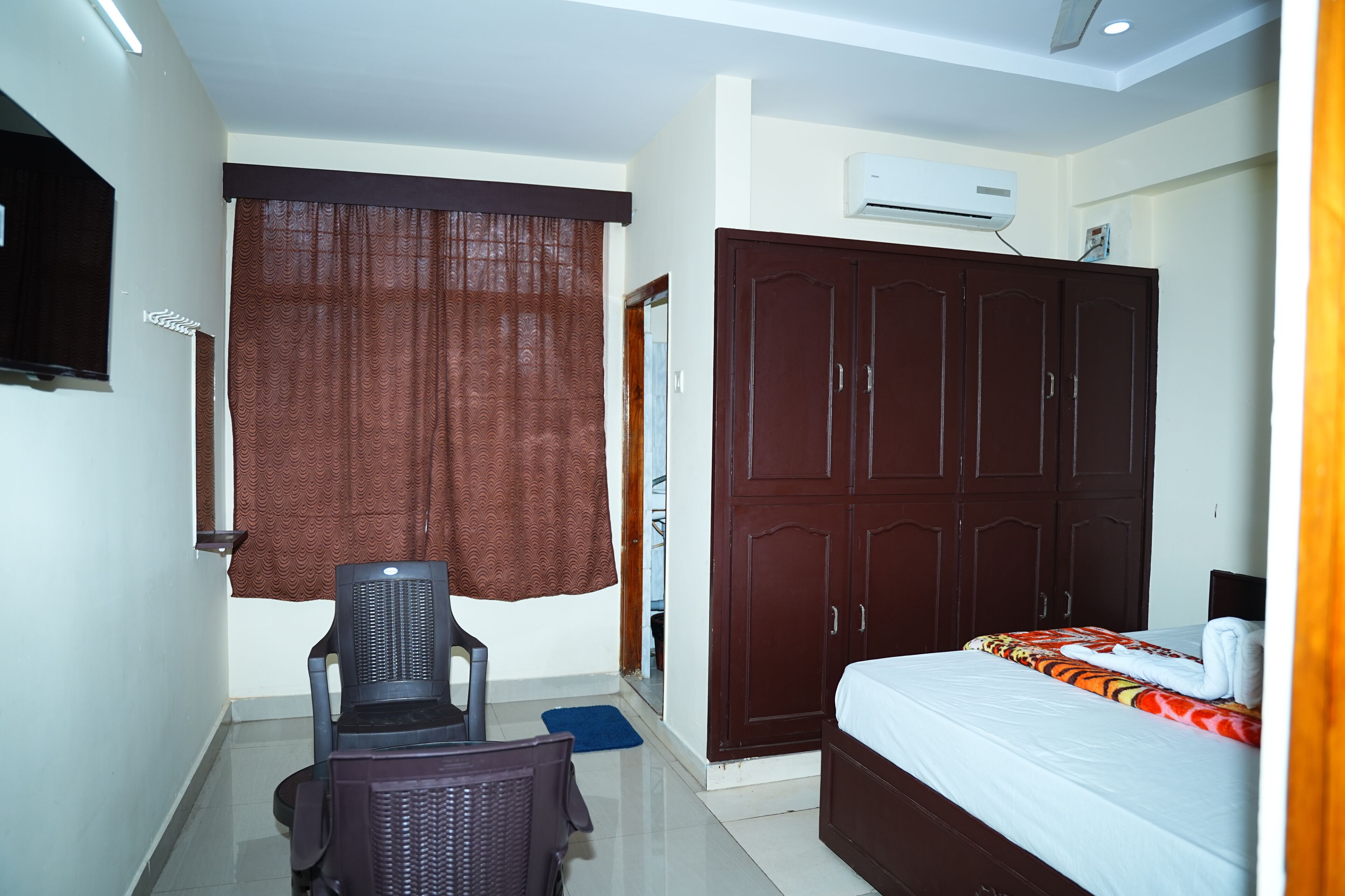 Habitación de hotel con cama, armario, aire acondicionado y un escritorio con silla.