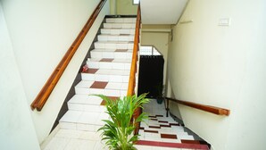 A staircase with wooden handrails, white and brown patterned steps, and a potted plant at the bottom. - SV Grand (Kakinada)