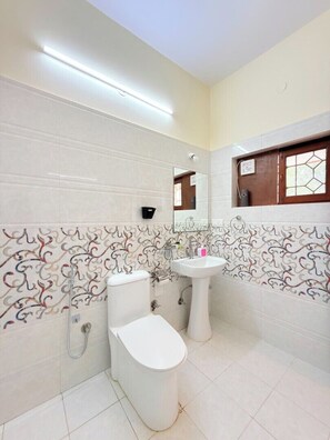Een badkamer met toilet, wastafel en spiegel.