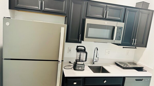 A compact kitchen with a refrigerator, microwave, coffee maker, sink, and dishwasher. - Cosy 1-bedroom house with AC in Haines City (Haines City)