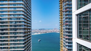 A high-rise building with multiple balconies overlooking a body of water. - Luxury 1BR Marina & Harbor View Beachfront (Dubai)