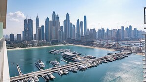 A marina with boats docked, a city skyline in the background, and a clear sky. - Luxury 1BR Marina & Harbor View Beachfront (Dubai)