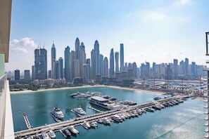 Ein Yachthafen mit vertäuten Booten, im Hintergrund ein Stadtpanorama und ein klarer Himmel.