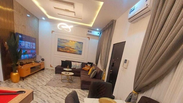 Una sala de estar moderna con un televisor de pantalla plana, un sofá, una mesa de comedor preparada para cuatro personas y piso de mármol.
