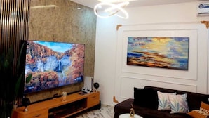 Una sala de estar moderna con un televisor de pantalla plana, un sofá, una mesa de centro y un cuadro en la pared.