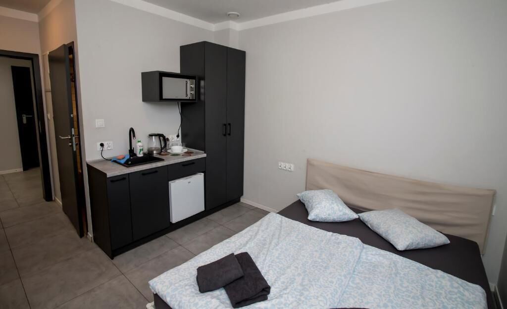 Una habitación de hotel con una cama, un pequeño rincón americano, un microondas y una puerta que da a otra habitación.