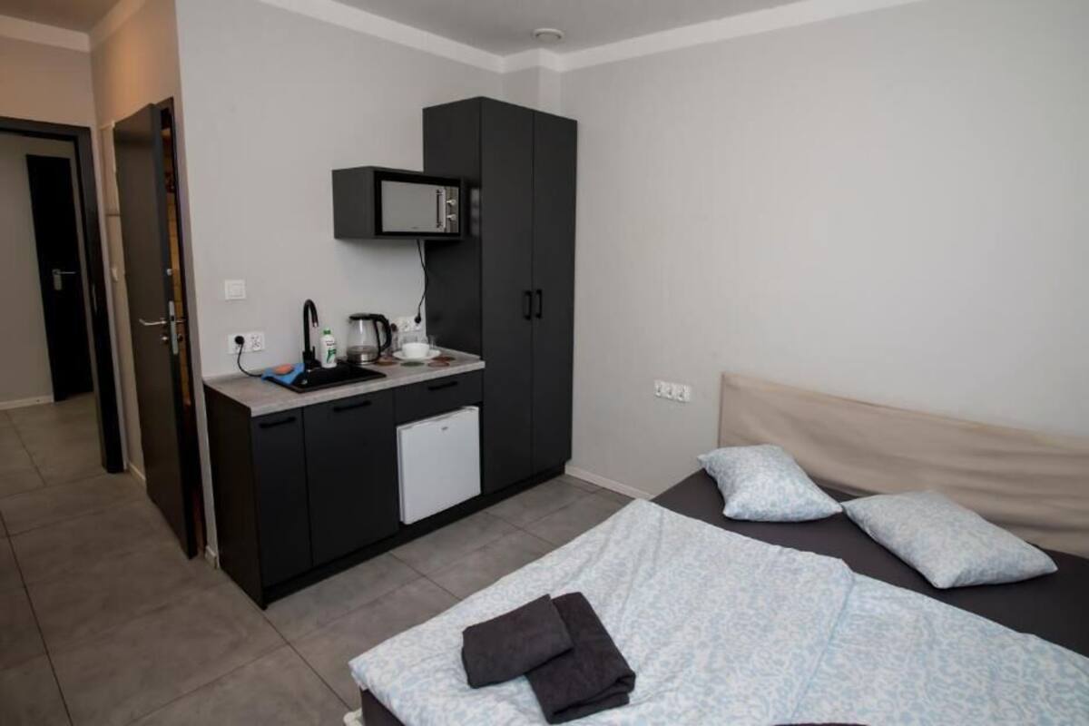 Une chambre d’hôtel comprenant un lit, une petite kitchenette, un four à micro-ondes et une porte donnant sur une autre pièce.