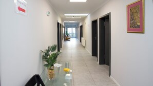 A hallway with a glass table, chairs, a potted plant, and a framed artwork on the wall. - Mia Mia House (Katowice)