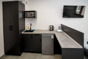 Una kitchenette funcional con microondas, refrigerador y cafetera.