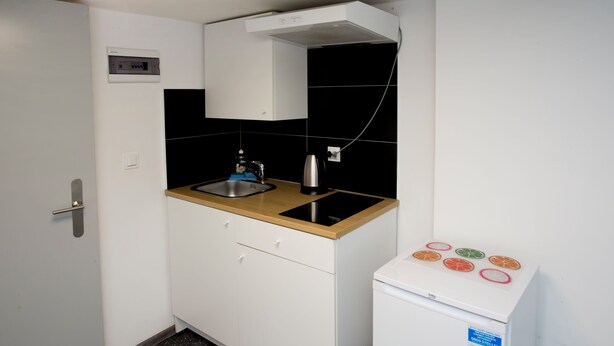 A compact kitchen with a sink, stove, and a small refrigerator. - Mia Mia House (Katowice)
