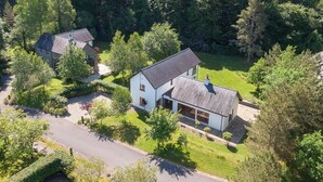 Ett bostadsområde med två hus omgivna av tät skog, en klar himmel och ett kuperat landskap i bakgrunden.