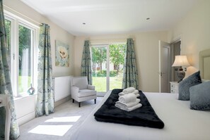 Un dormitorio con cama, una silla, un radiador, una lámpara y vistas al exterior.