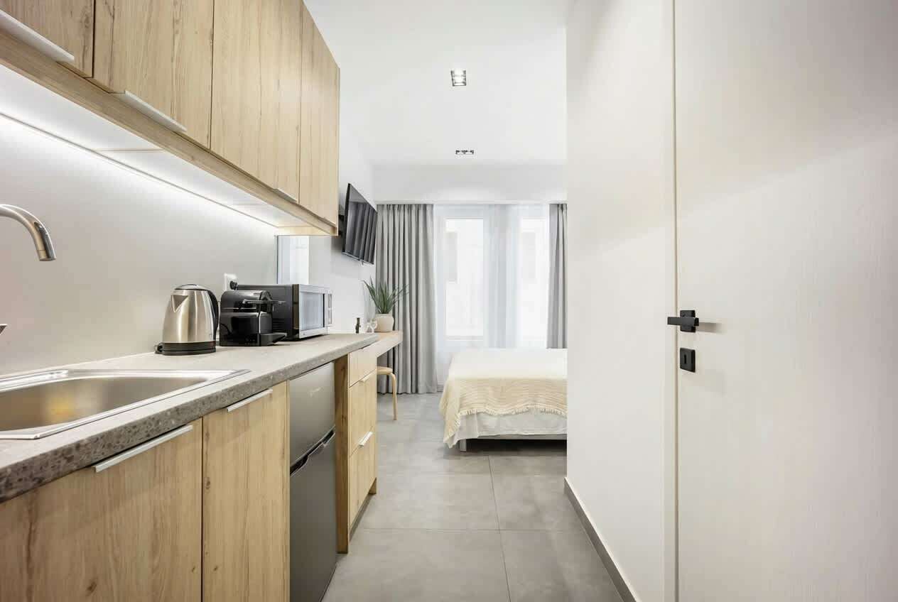 A compact hotel room with a kitchenette, a bed, and a television.