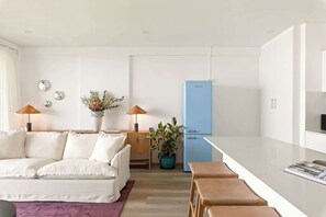 Una cocina moderna con un refrigerador azul, un sofá blanco y un comedor con taburetes.