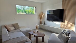 En moderne stue med sofa, sofabord og fjernsyn monteret på væggen.