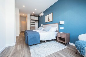 A bedroom with a bed, bedside table, nightstand, and a blue wall. - Dúplex Príncipe de Canalejas (Madrid)