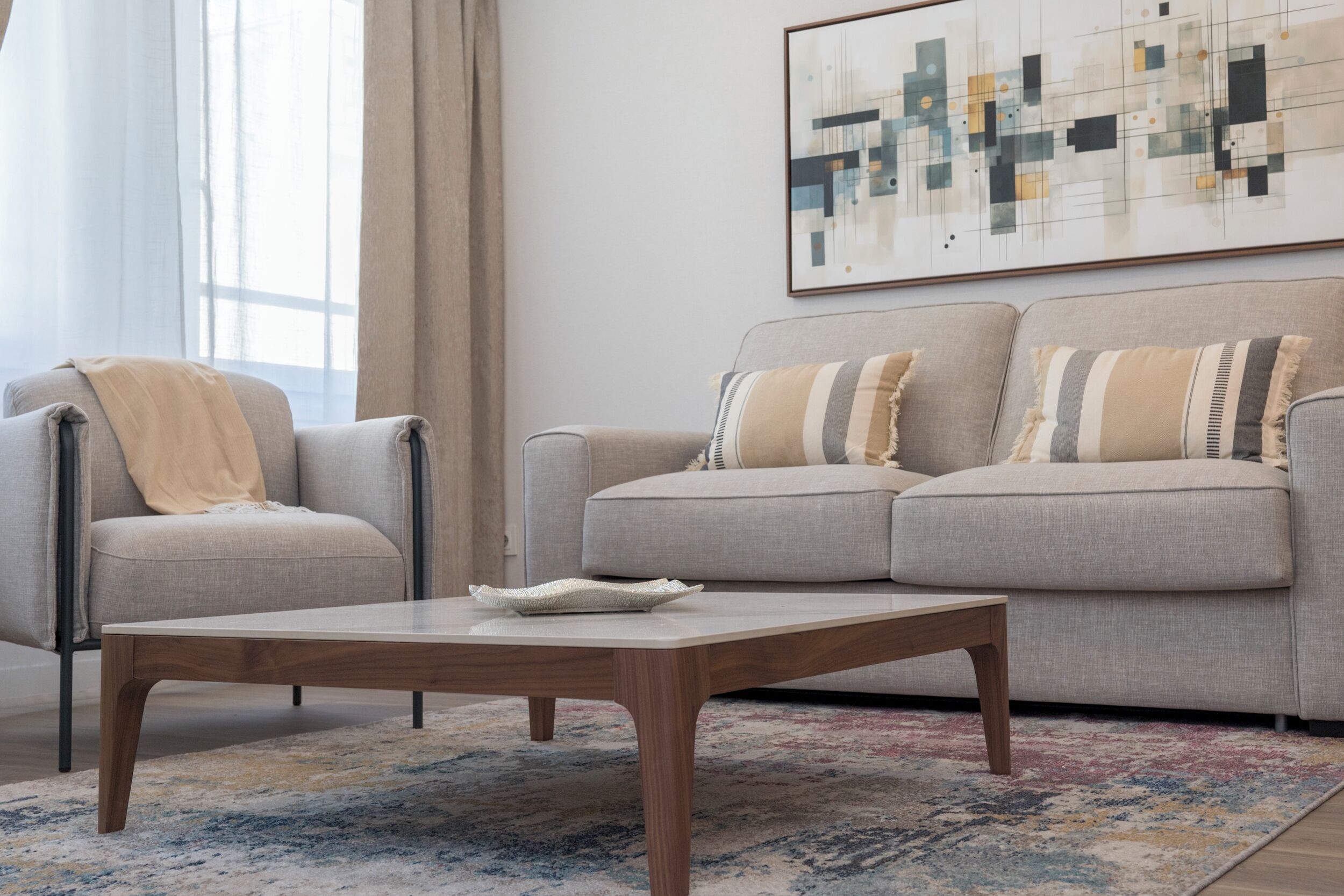 A living room with a sofa, a coffee table, and a large abstract painting on the wall.