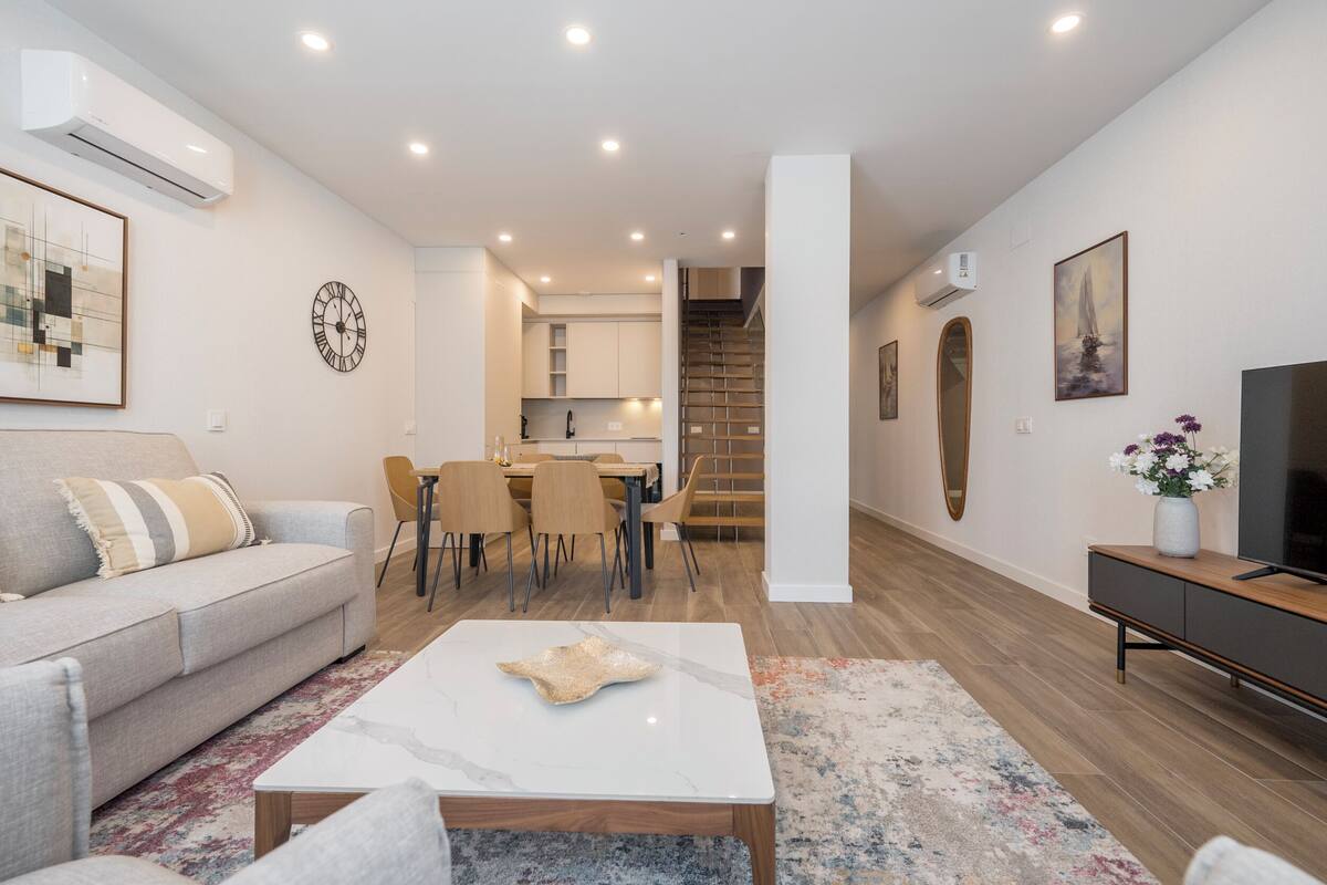 Una sala de estar moderna con un sofá, una mesa de centro y un mueble para televisión.